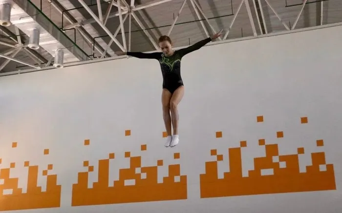 Гимнастка выполняет прыжки на батуте